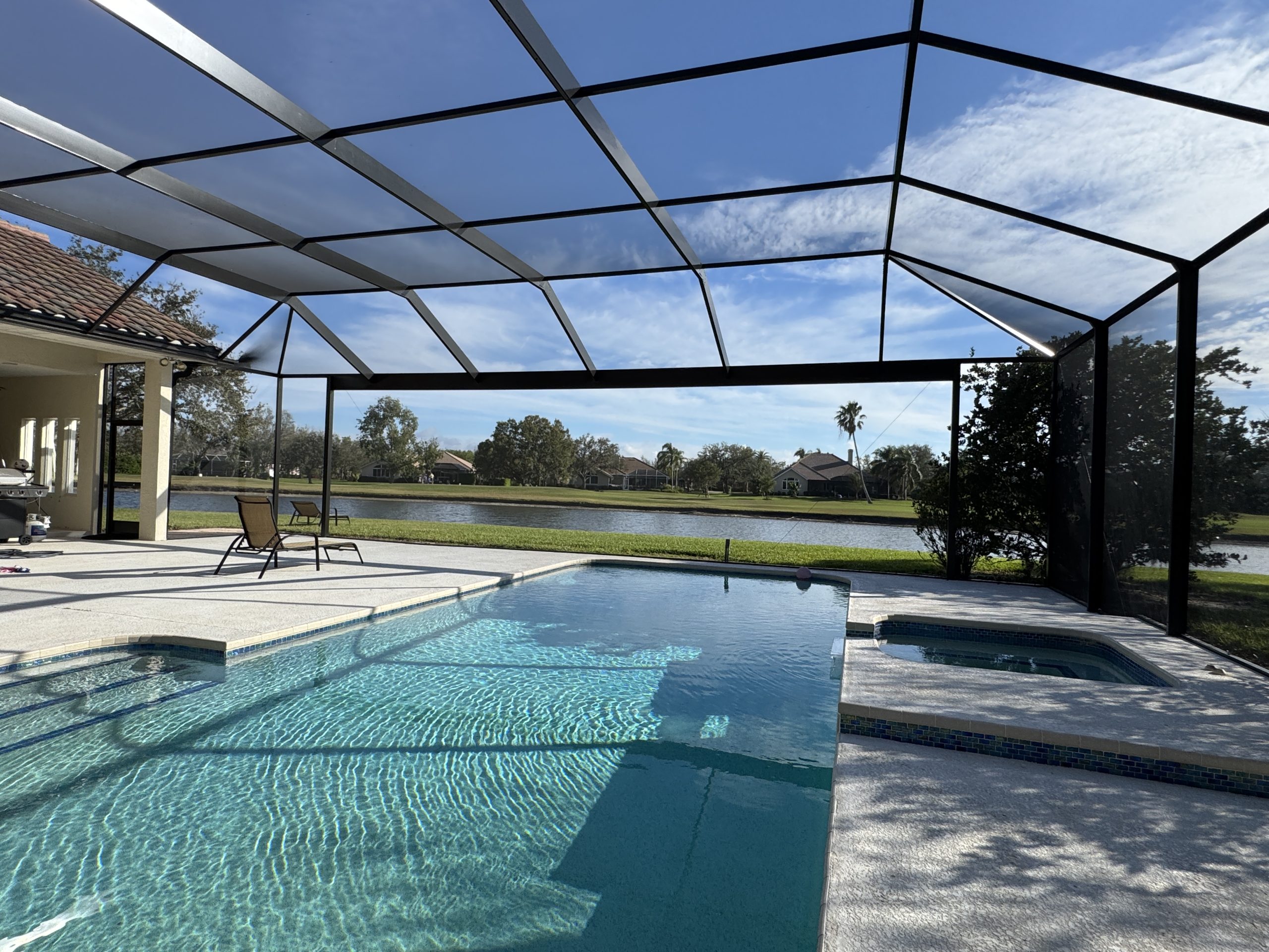 Custom pool screen enclosure with swimming pool, paved deck and overhead shade panels